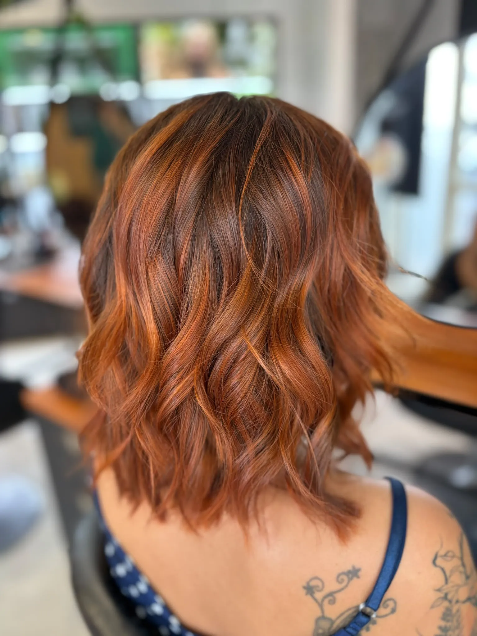 Dos de cheveux mi-longs ondulés roux cuivré, reflets orangés dans les longueurs