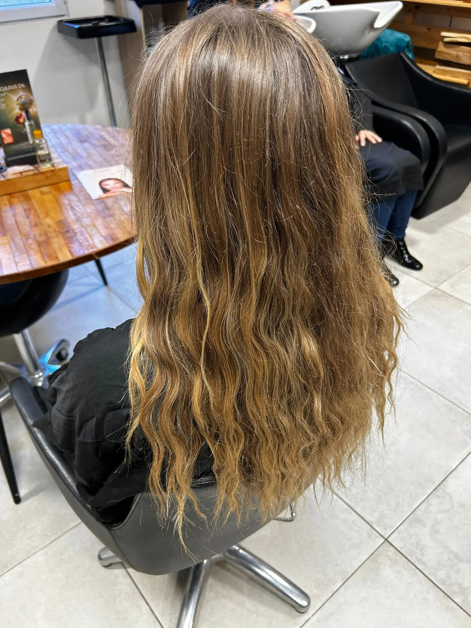 Mèches blond doré sur cheveux longs ondulés réalisées dans un salon de coiffure à Narbonne
