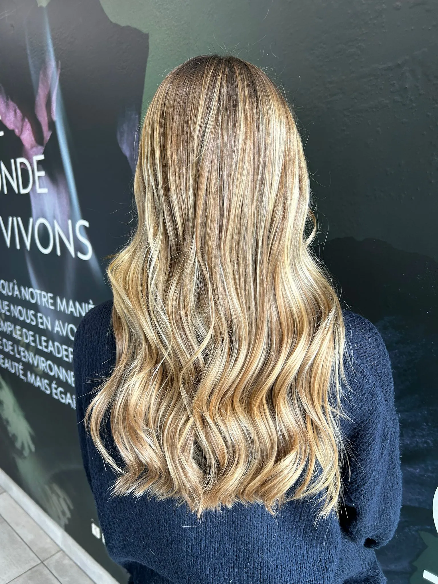 Mèches blondes lumineuses sur une chevelure longue et ondulée réalisées dans un salon de coiffure à Narbonne