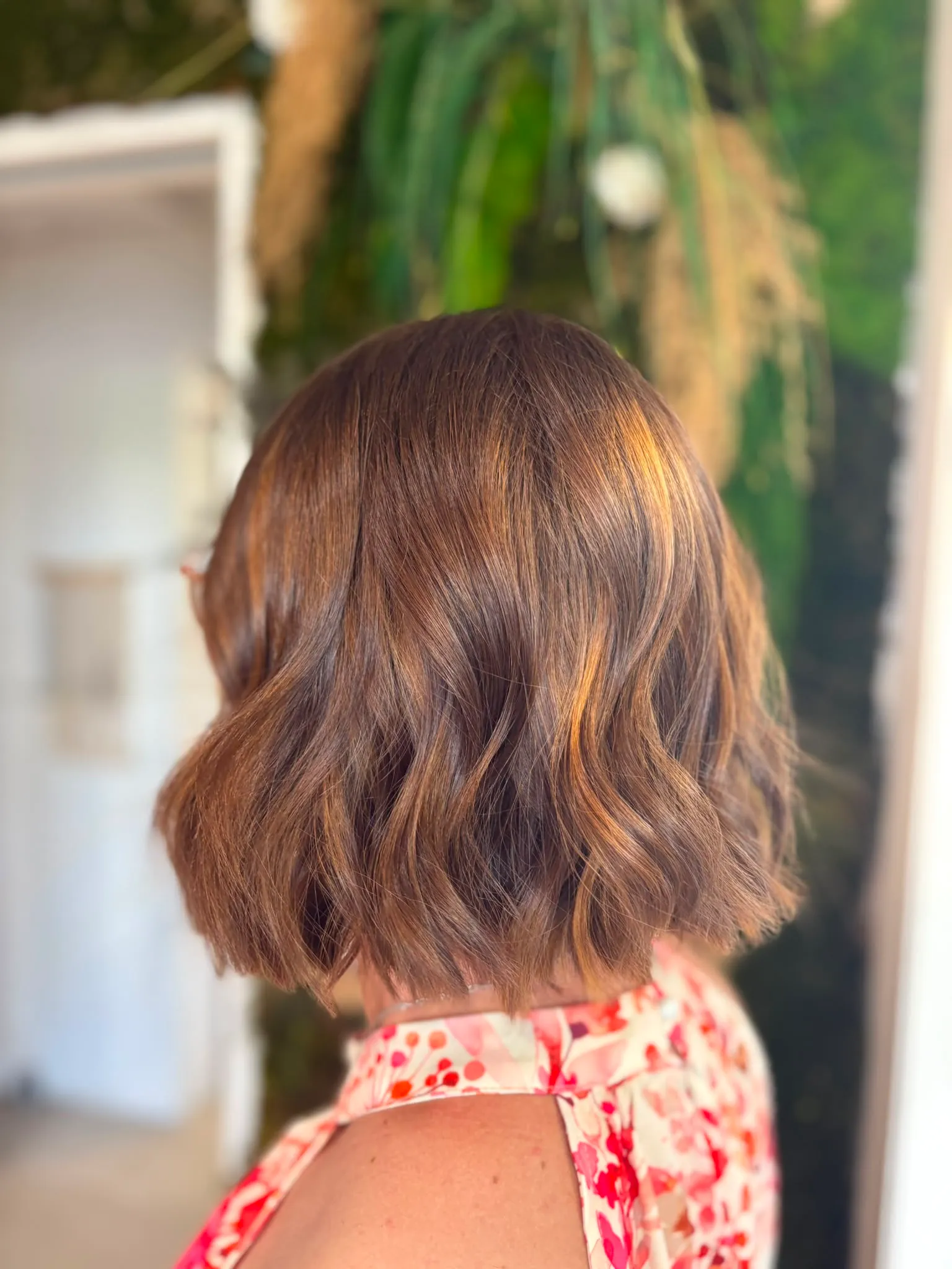 Coupe au carré brune aux reflets cuivrés dans un intérieur végétalisé