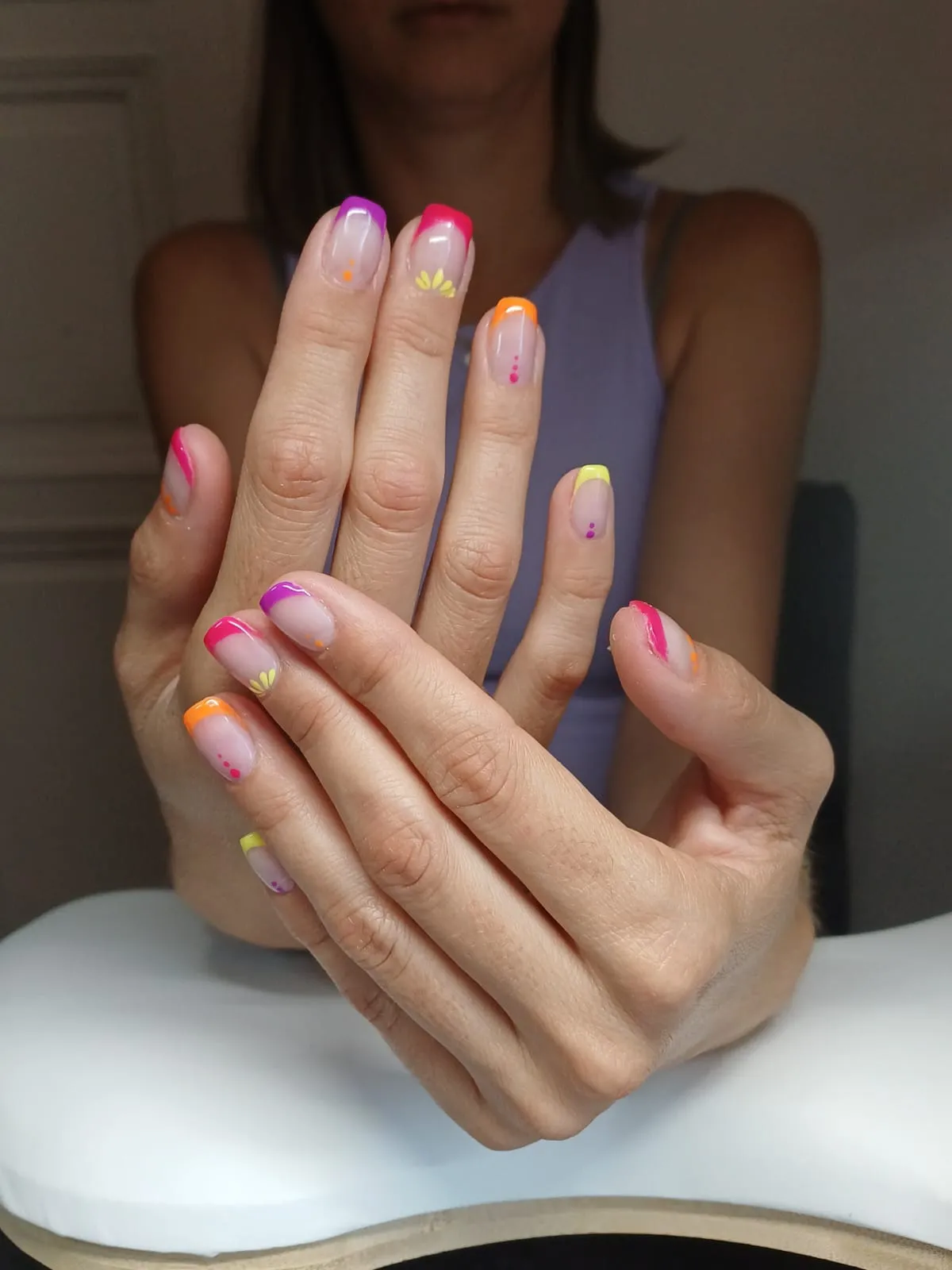Mains avec des ongles nude aux pointes colorées et de petits motifs floraux