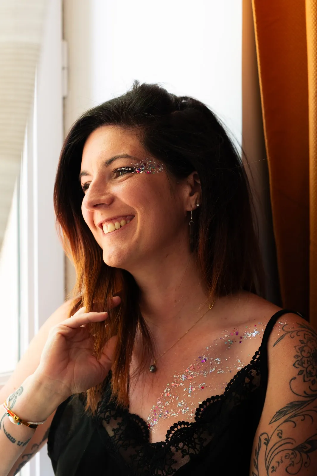 Femme souriante portant un maquillage pailleté sur le visage et le décolleté