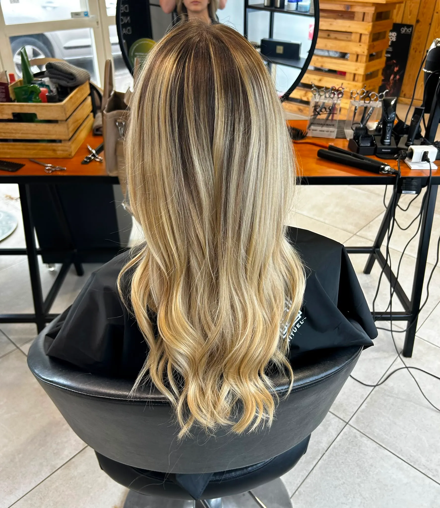 Mèches blondes lumineuses sur cheveux longs ondulés