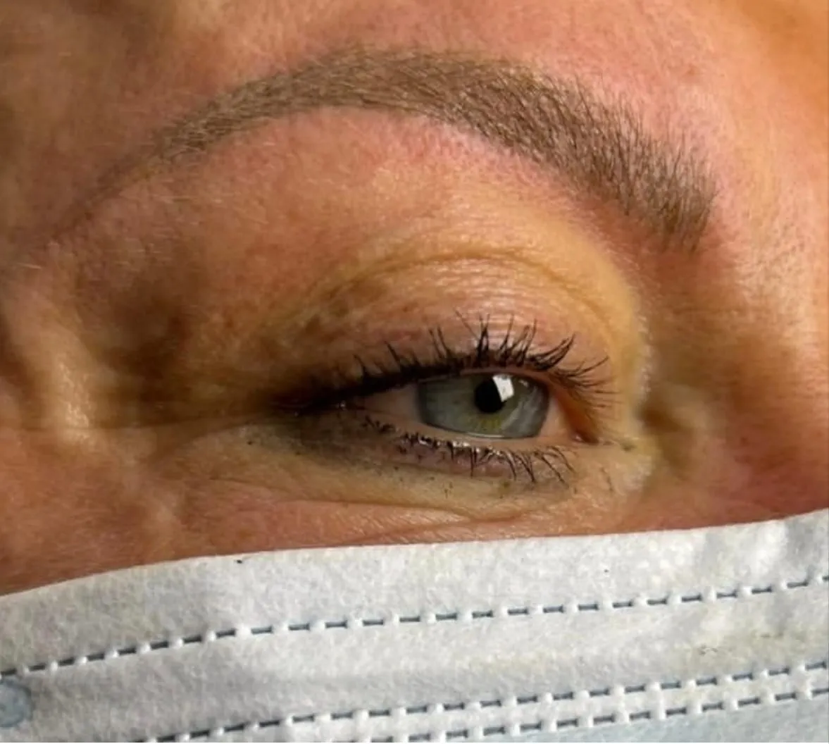 Gros plan sur une extension de cils soulignant le regard, avec masque de protection